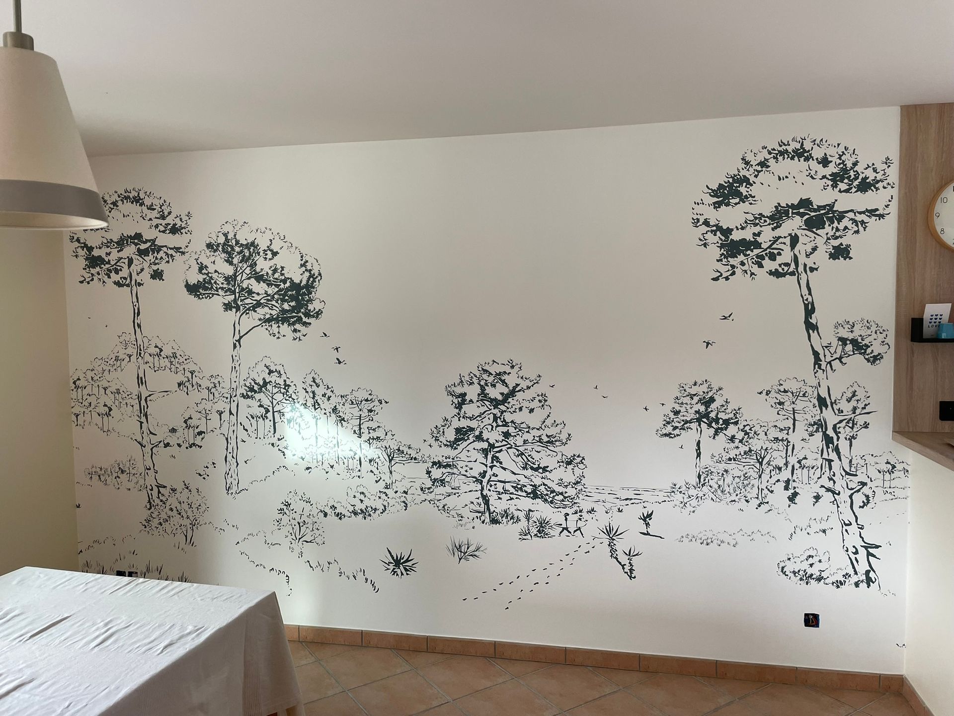 Mur blanc avec des silhouettes d'arbres vert foncé.