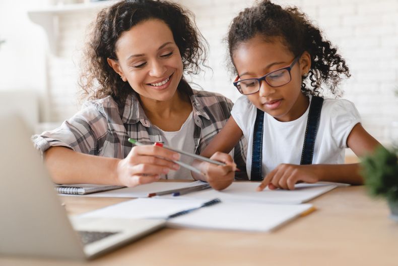 Deux personnes autour d’une table examinent des documents à côté d’un ordinateur portable ; l’une d’elles montre quelque chose du doigt avec un stylo, dans un espace de travail lumineux
