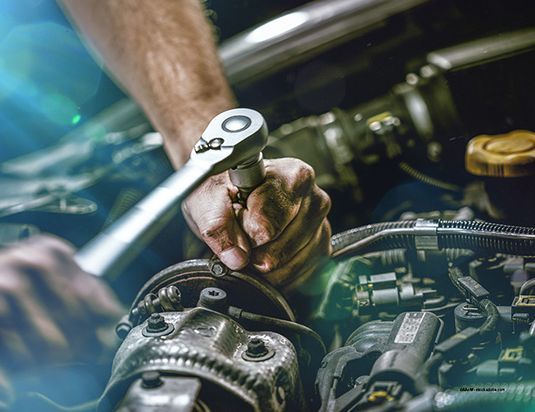 Leupold Fahrzeuge und Motoren e.K. Kfz-Mechaniker arbeitet an einer offenen Motorhaube eines Fahrzeugs