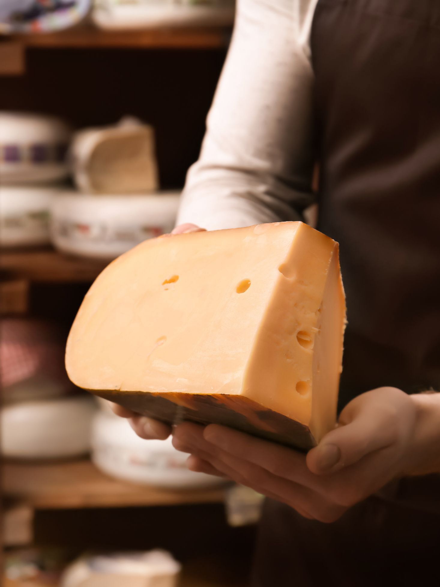 Épicier montrant un morceau de fromage.