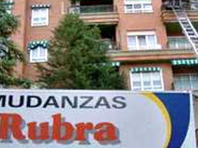 Un cartel de mudanzas rubra está frente a un edificio de ladrillos.