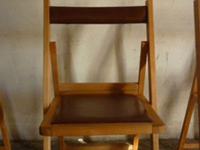 Una silla plegable de madera con un cojín marrón.