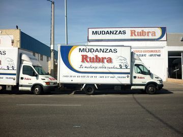 Dos camiones estacionados frente a un edificio que dice mudanzas rubra