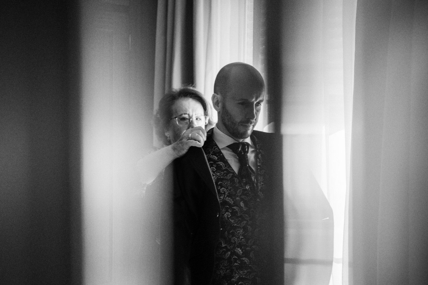 Hombre vestido de etiqueta, recibiendo ayuda de una persona para ajustar su chaqueta