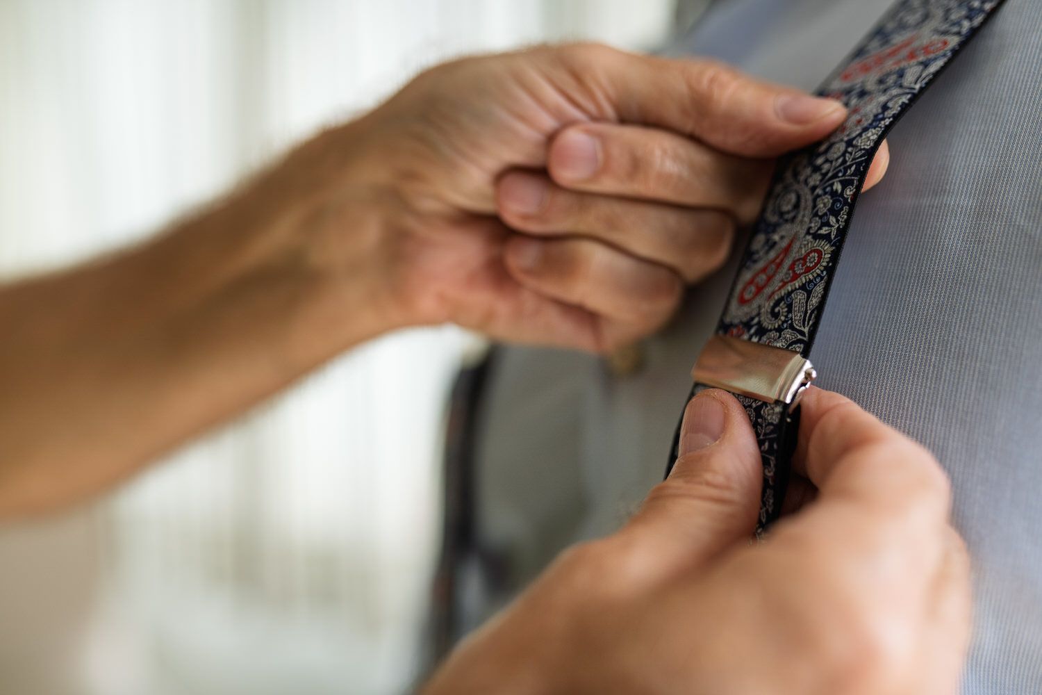 Manos ajustando una tira de liguero estampada en una camisa azul claro.