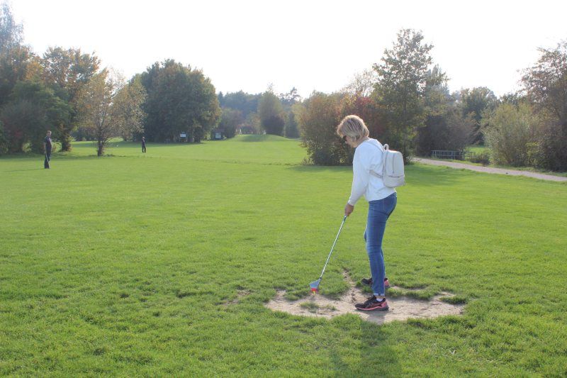 Eine Frau spielt an einem sonnigen Tag in einem Park Golf.