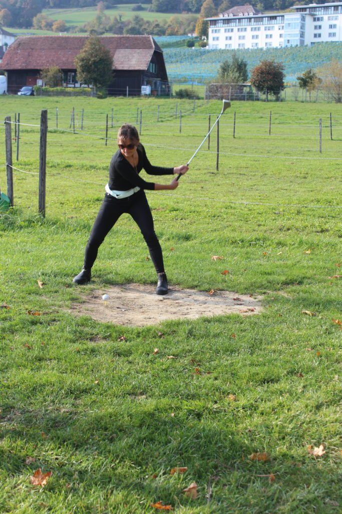 Eine Frau schwingt auf einem Feld einen Golfschläger.