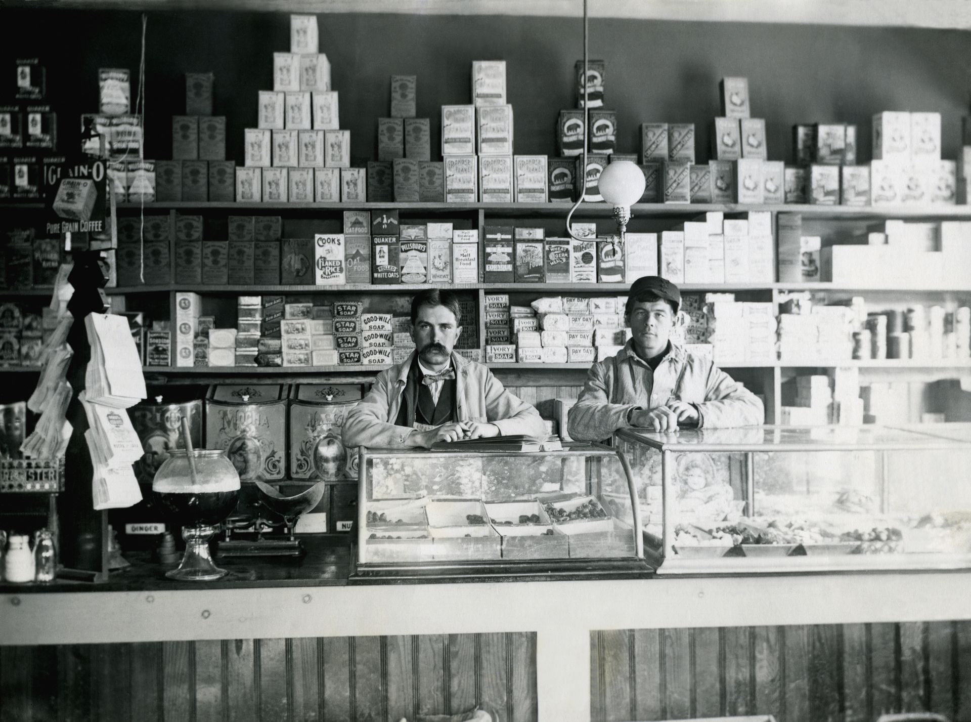 Photo vintage de deux hommes derrière un comptoir de boutique