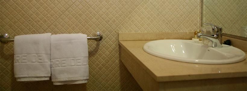 Un baño con lavabo, toallas y espejo.