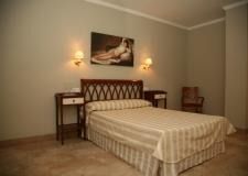 Un dormitorio con una cama, dos mesitas de noche, una silla y un cuadro en la pared.