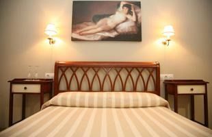 Un dormitorio con una cama, mesitas de noche y un cuadro en la pared encima de la cama.