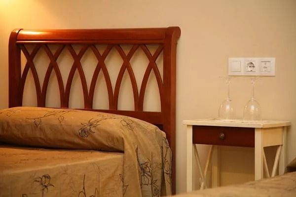 Un dormitorio con una cama y una mesita de noche con vasos encima.