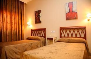 Una habitación de hotel con dos camas y un jarrón en la pared.