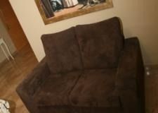 Un sofá marrón está sentado en una sala de estar al lado de un espejo.