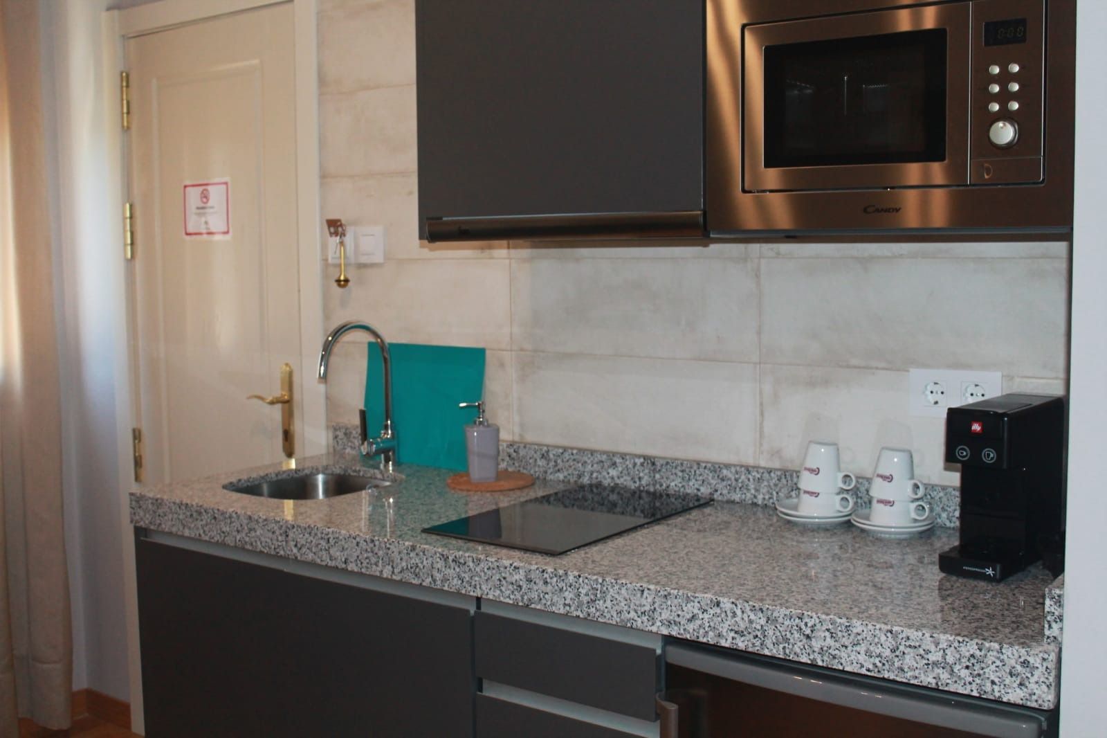 Una cocina con fregadero, estufa, microondas y lavavajillas.