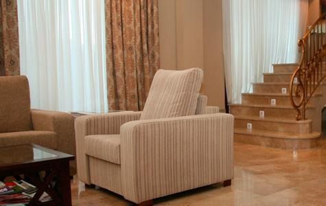 Una sala de estar con una silla, un sofá, una mesa de café y escaleras.