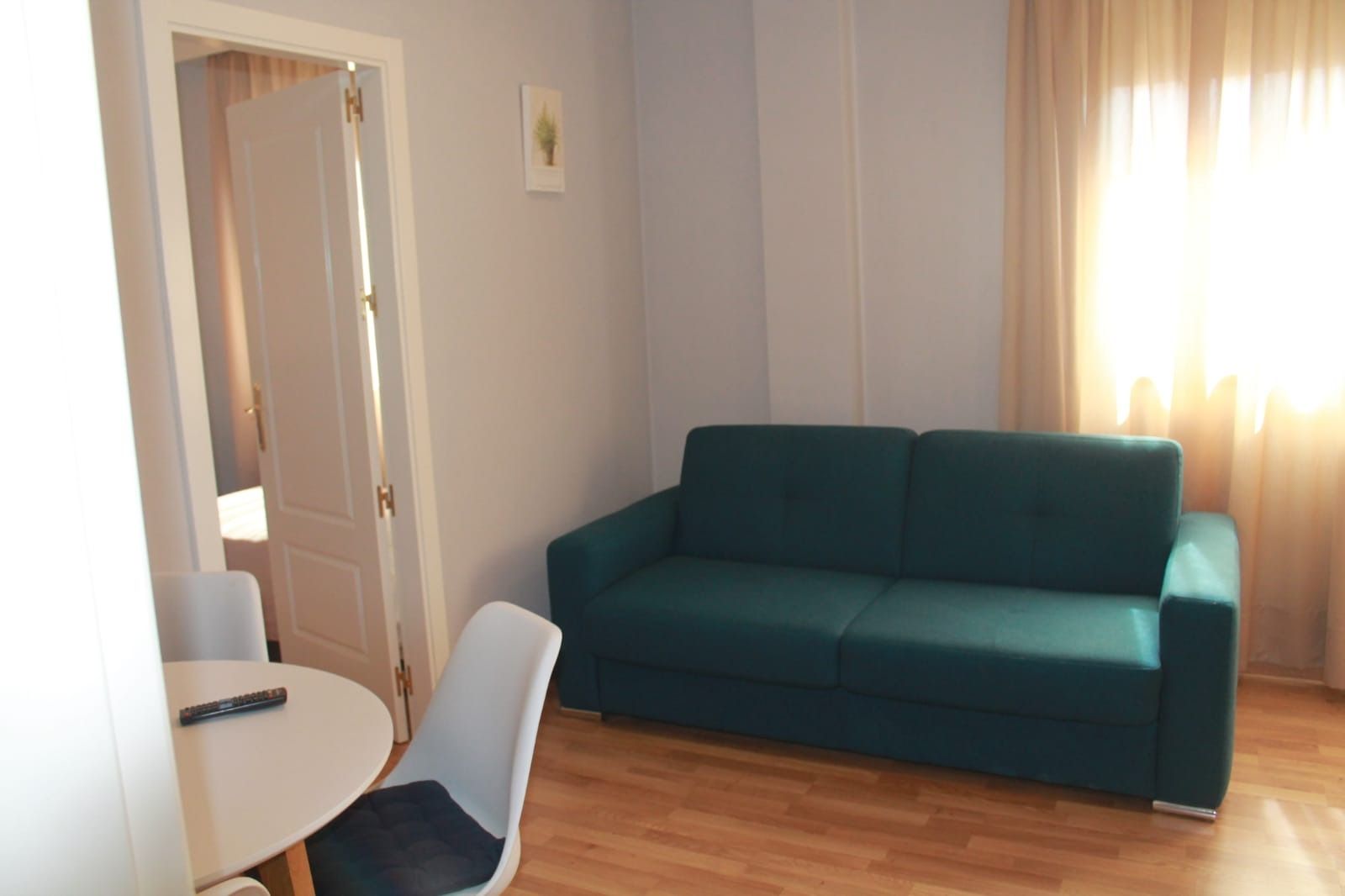 Una sala de estar con un sofá verde y una mesa blanca.