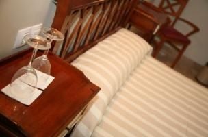 Hay dos copas de vino en una mesita de noche al lado de una cama.