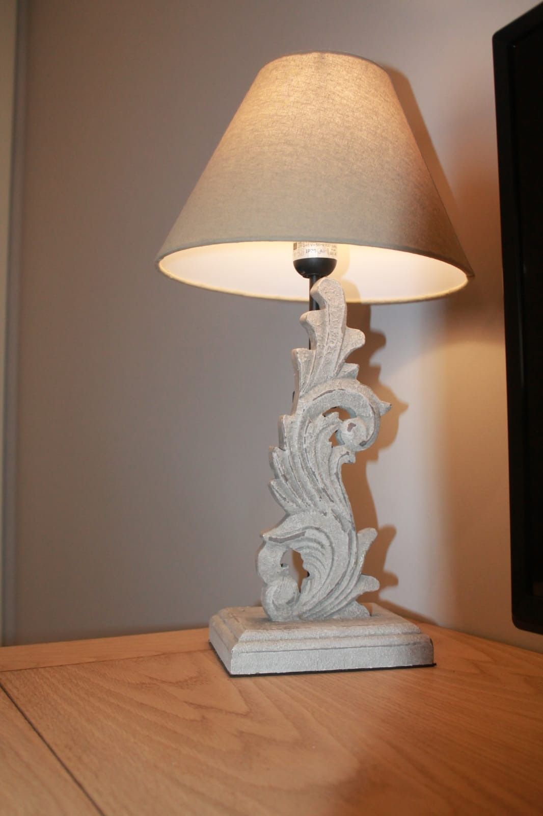 Una lámpara blanca con pantalla blanca está sobre una mesa de madera.