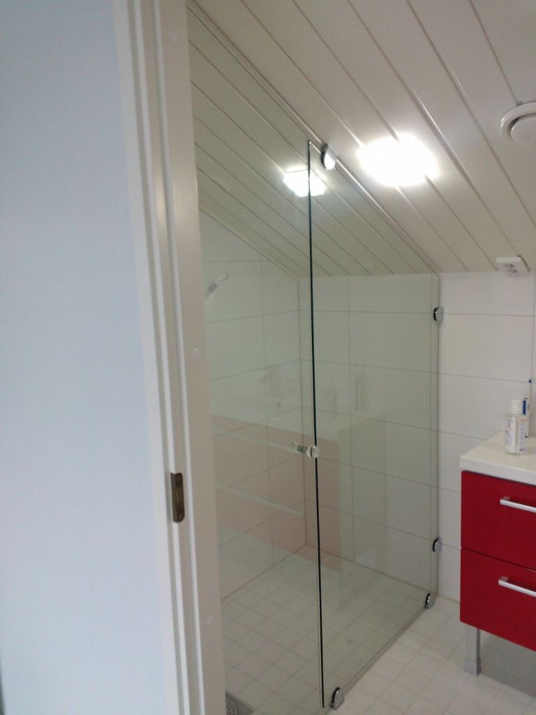 Lasinen suihkukaappi kylpyhuoneessa, jossa on punainen kaappi.