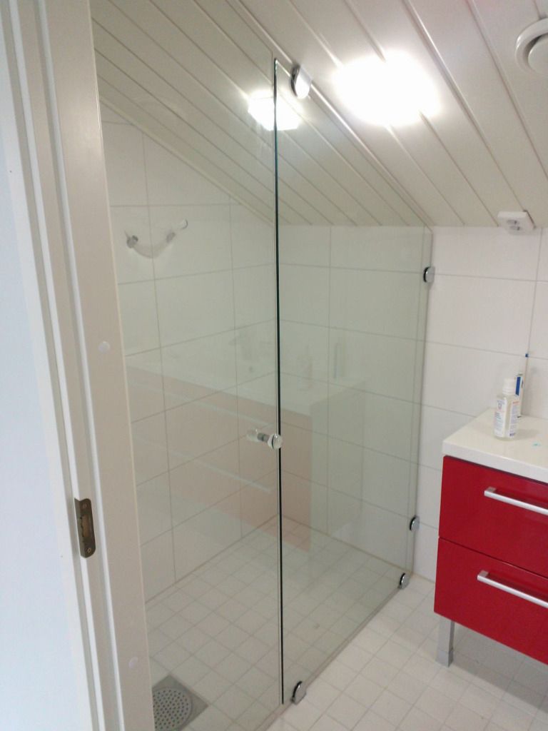 Kylpyhuone, jossa lasinen suihkukaappi, punainen pesuallas ja valkoiset laatat. Kulmikas katto upotetulla valaisimella.