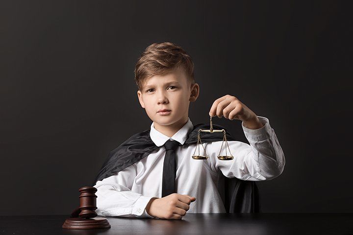 Jeune garçon tenant la balance de la justice dans les mains