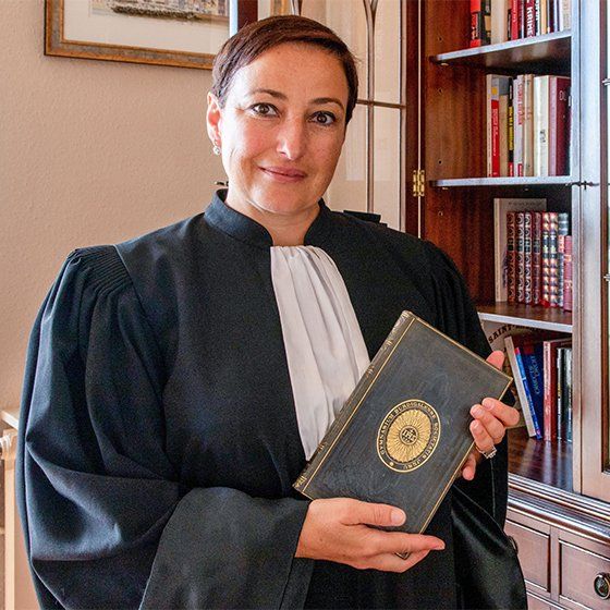 Maître Lorea CHIPI en robe d'avocat, tenant un livre doré entre ses mains