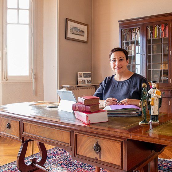 Maître Lorea CHIPI en robe d'avocat, assise devant son bureau, souriante