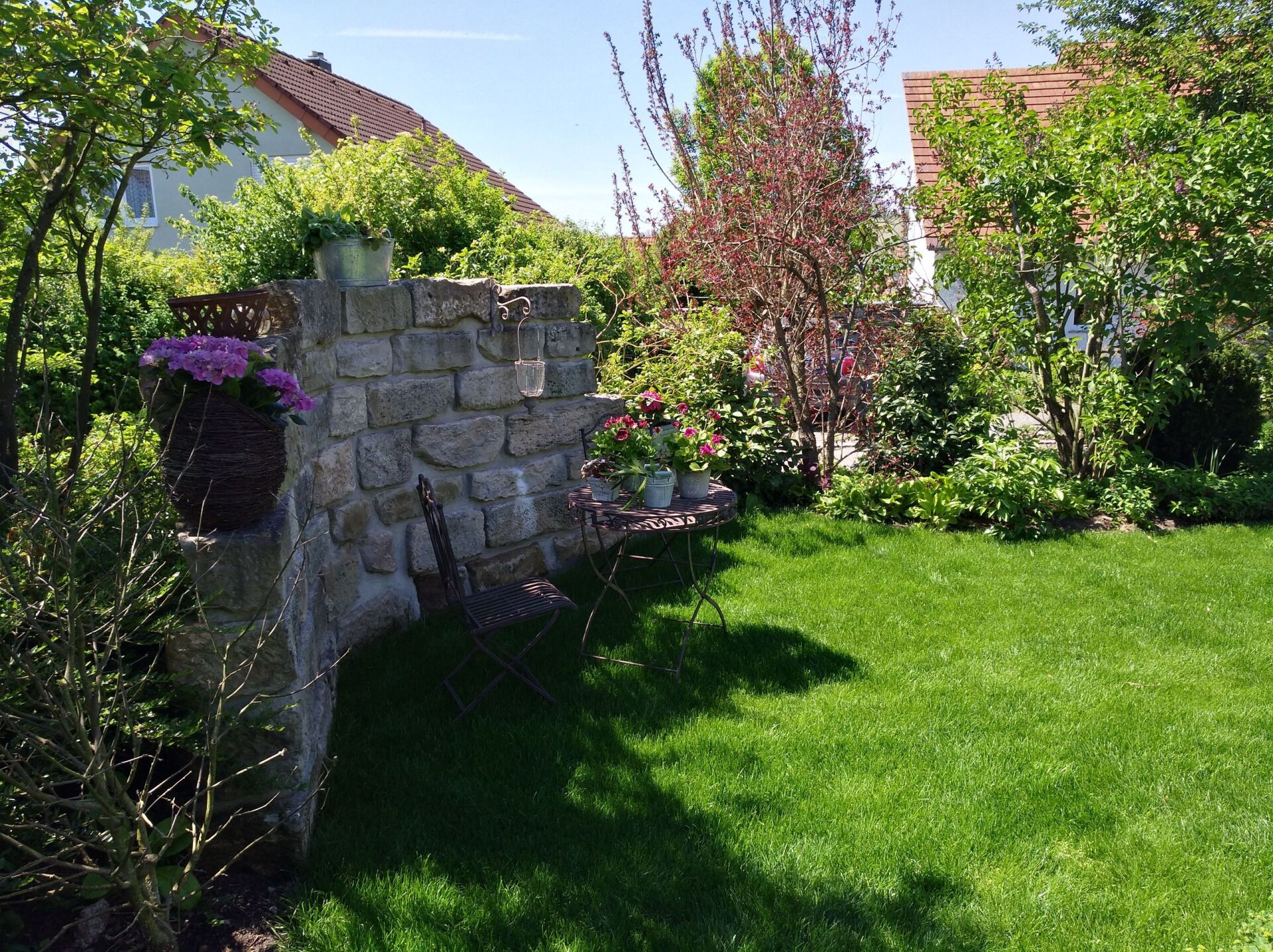 ein Tisch und ein Stuhl in einem Garten neben einer Steinmauer