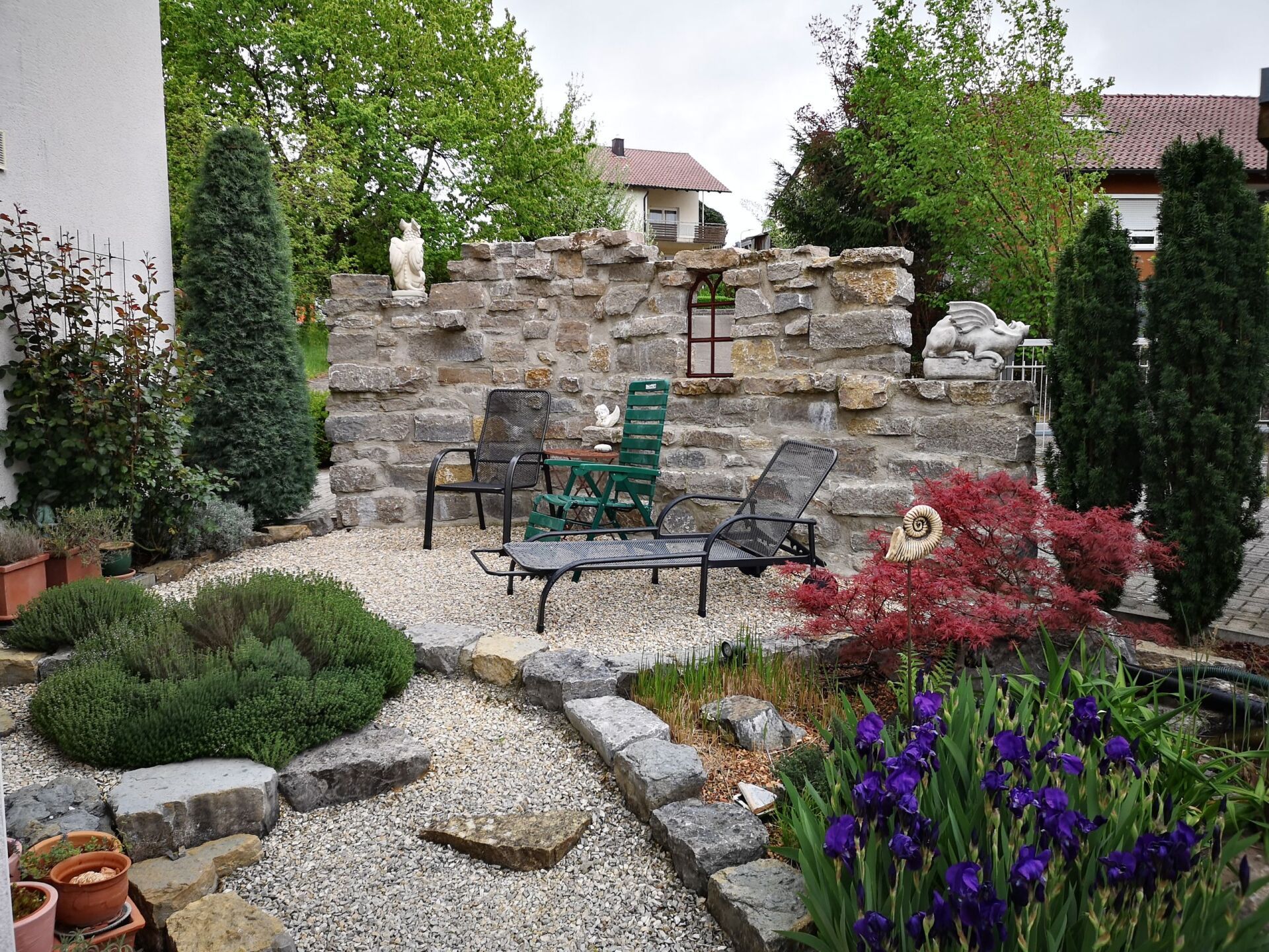 ein Garten mit Stühlen und einer Steinmauer