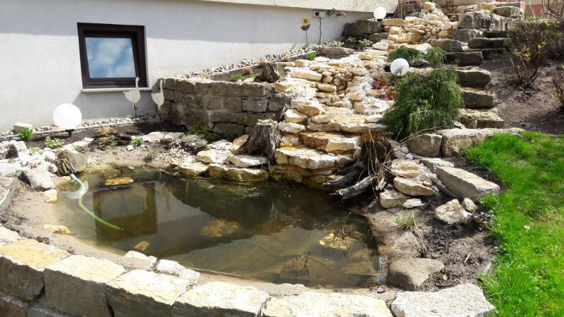 Natürlich gestalteter Teich mit Steintreppe für Wasserlauf in einem Garten