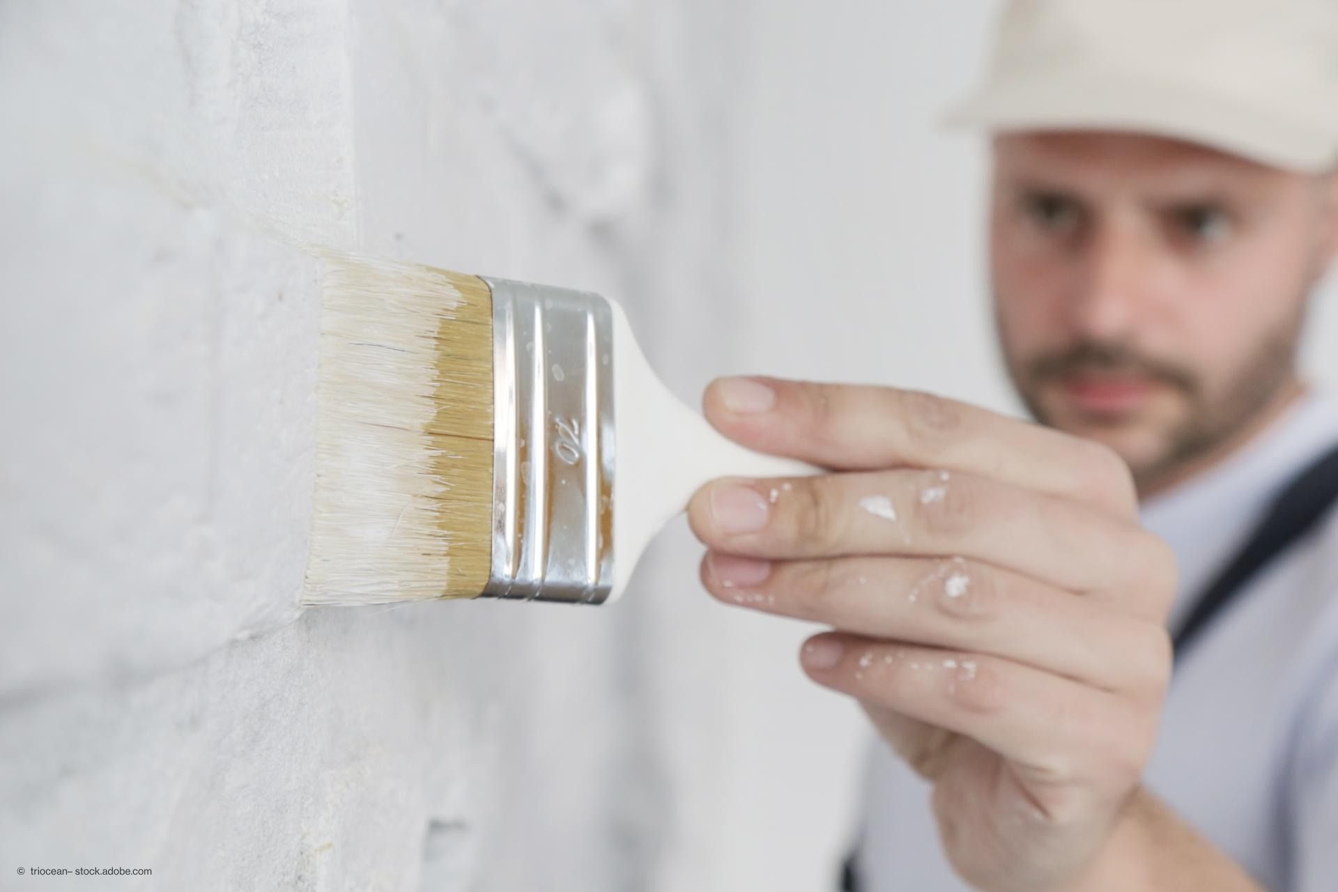 Ein Maler malt eine Wand in Weiß