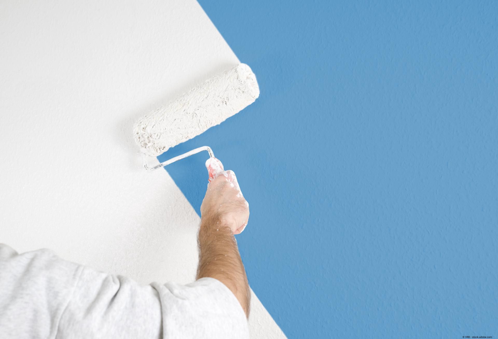 Ein Maler malt eine Wand in Hellblau