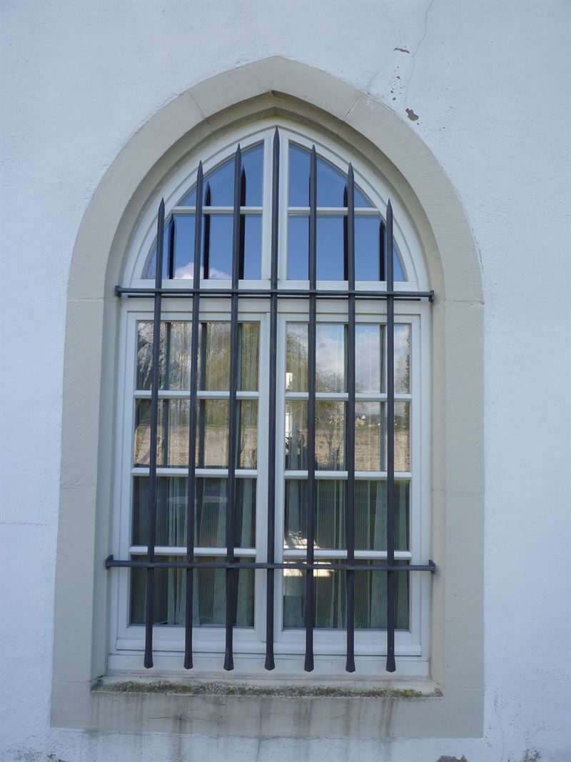 Ein weißes Bogenfenster mit Gittern darum