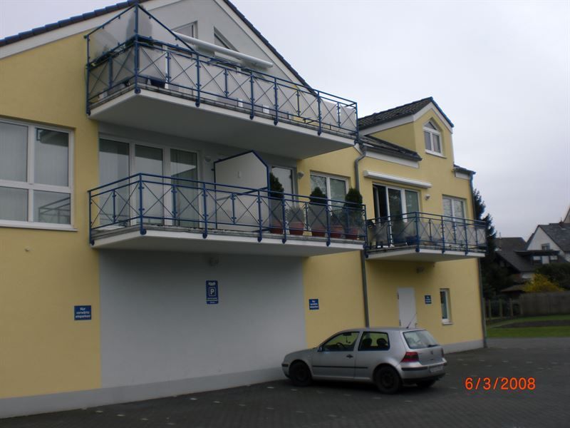 Ein Auto parkt vor einem gelben Gebäude mit Balkonen