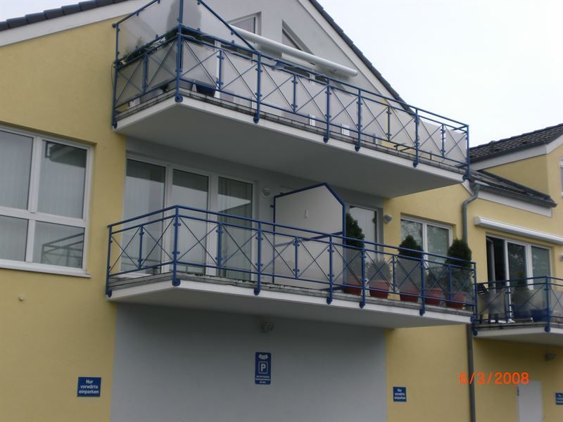 Ein gelbes Gebäude mit einem Balkon und einem blauen Geländer