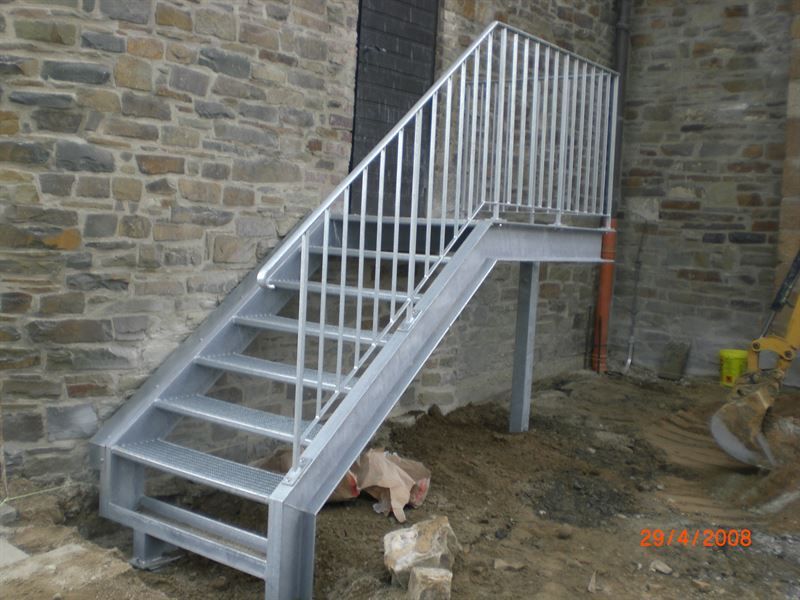 Vor einem Steingebäude wird eine Metalltreppe gebaut.