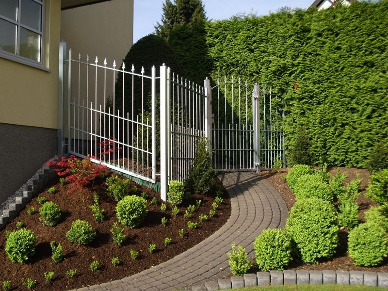 Ein weißer Zaun umgibt einen üppigen grünen Garten