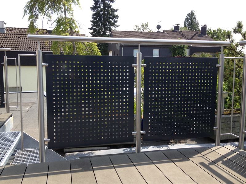 Ein Zaun mit Löchern darin ist auf einem Balkon