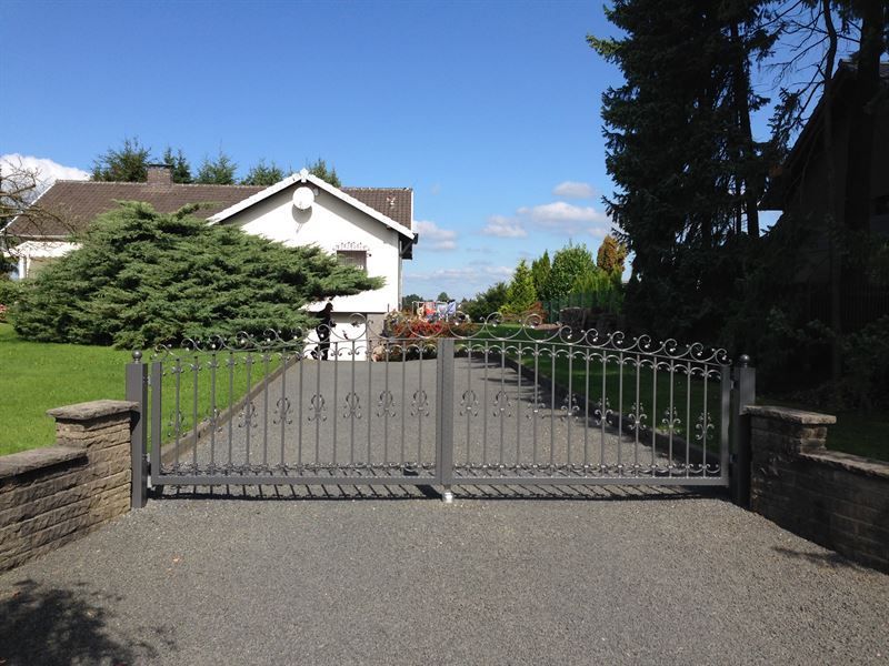 Eine eingezäunte Auffahrt, die zu einem weißen Haus führt