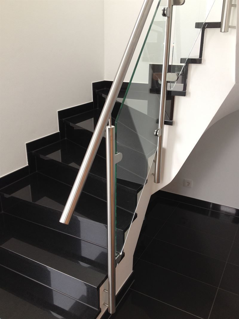 Eine Treppe mit schwarzen Stufen und einem Glasgeländer