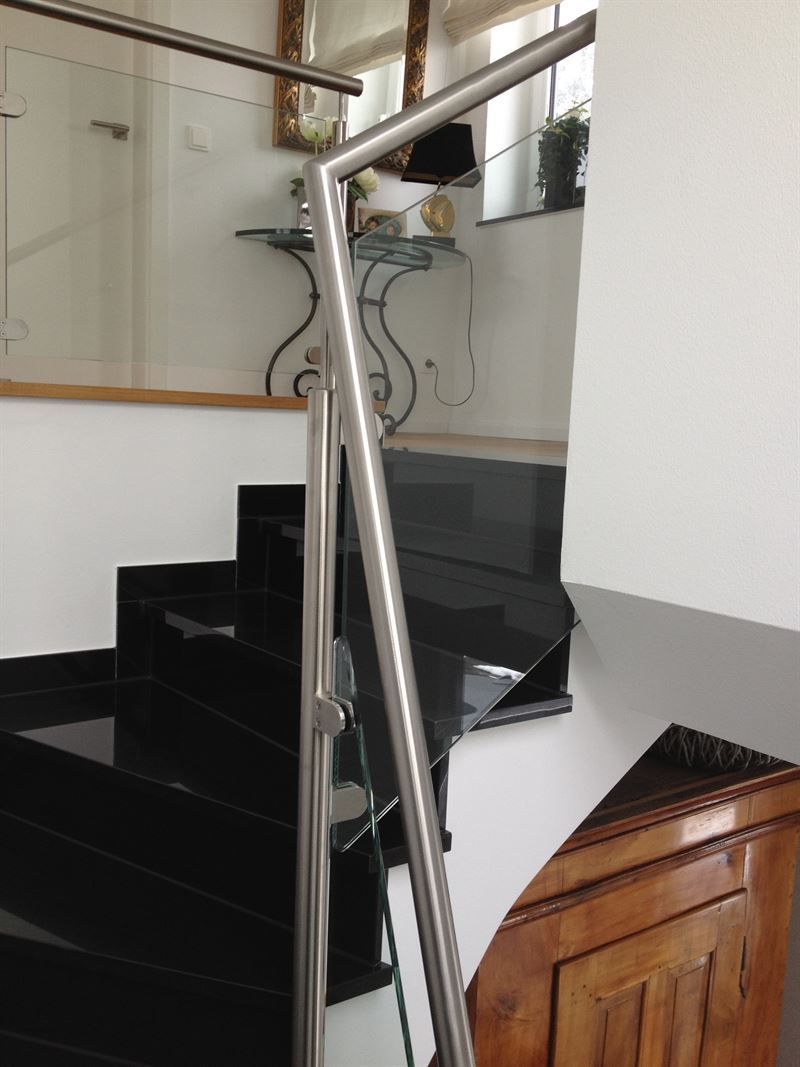 Eine Treppe mit schwarzen Stufen und einem Edelstahlgeländer