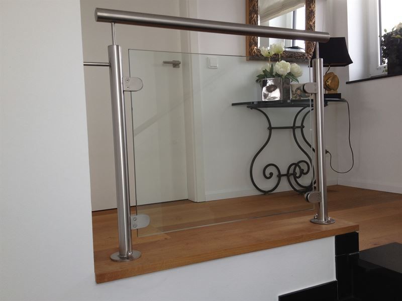 Eine Treppe mit einem Glasgeländer und einem Tisch mit Blumen darauf