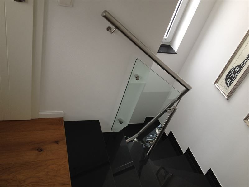 Eine Treppe mit schwarzen Stufen und einem Glasgeländer