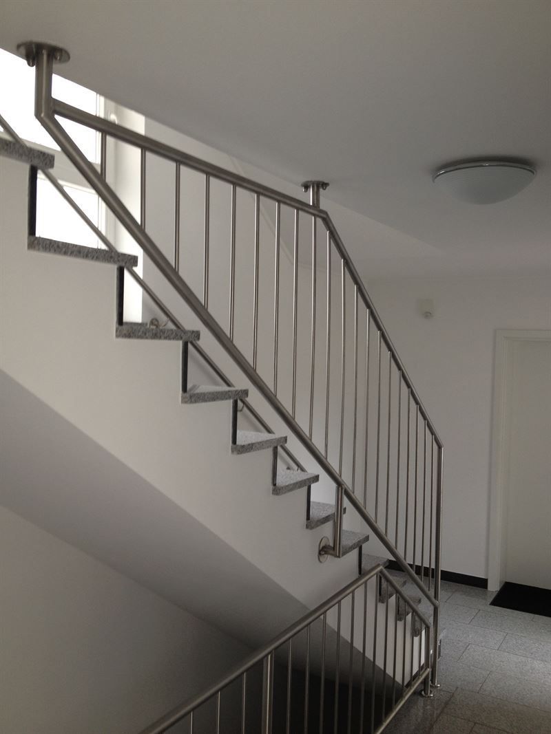 Eine Treppe mit einem Edelstahlgeländer in einem Flur
