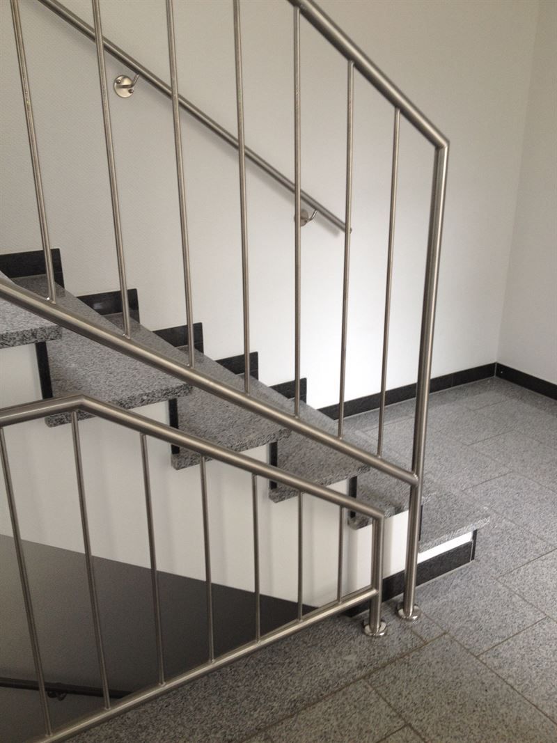 Eine Treppe mit Edelstahlgeländer und schwarzen Stufen