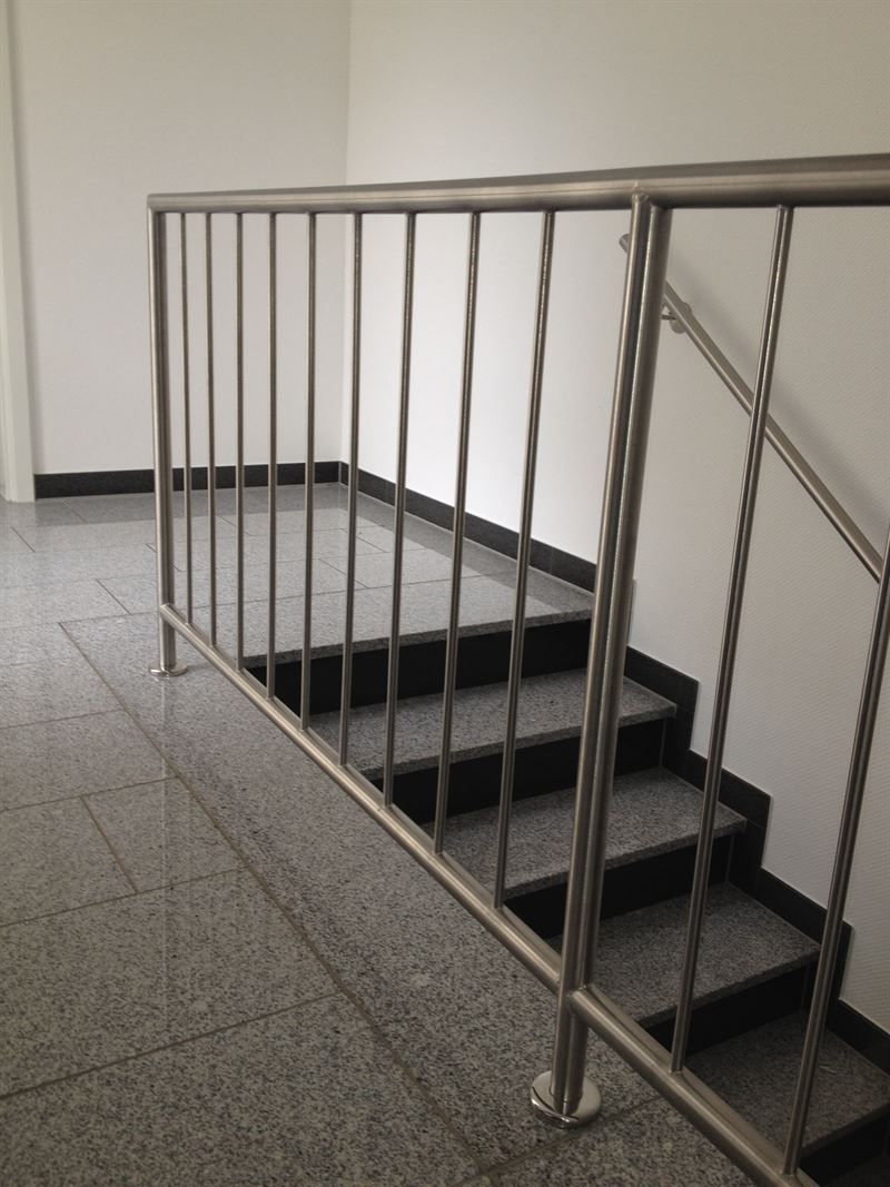 Eine Treppe mit einem Edelstahlgeländer in einem Gebäude