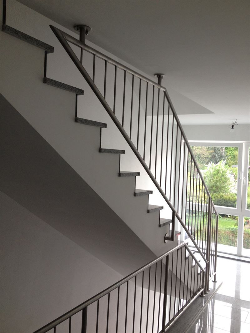 Eine Treppe mit einem Edelstahlgeländer in einem Gebäude
