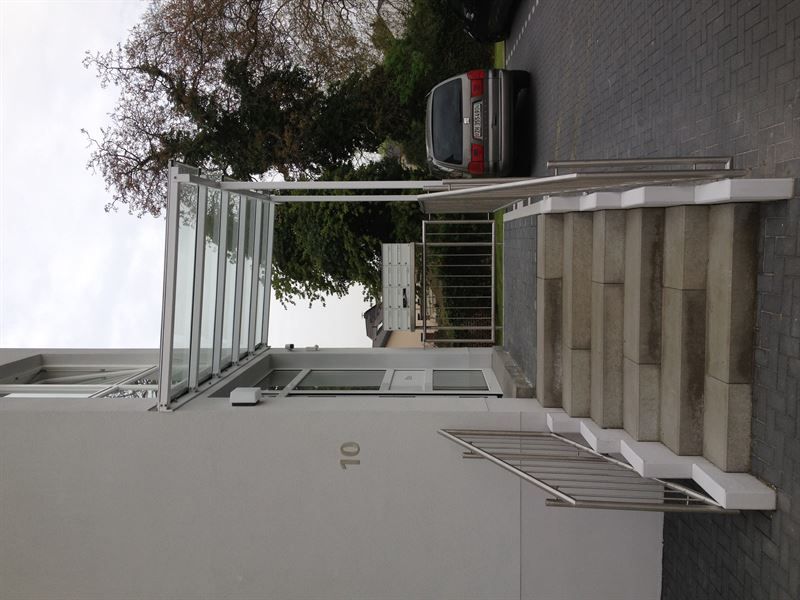 Vor einem Gebäude mit der Nummer 10 steht ein Auto