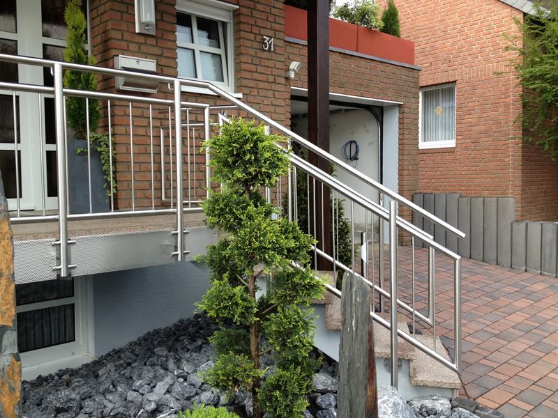 Eine Treppe mit Edelstahlgeländer vor einem Backsteinhaus